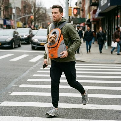 Sac a dos chien Fusion Maître marchant dans la rue avec son Yorshire dans le sac orange